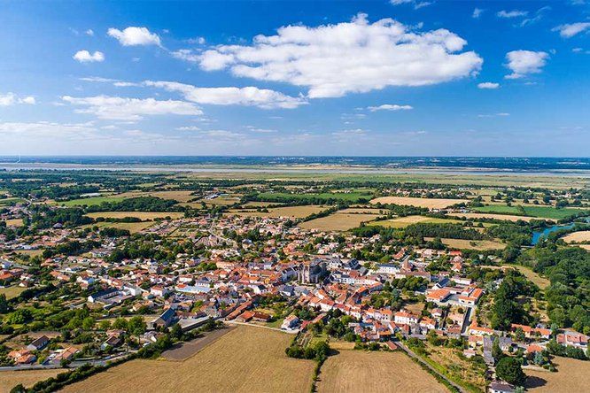 vue aérienne d'un village aux maison de tuiles, bordé de champs