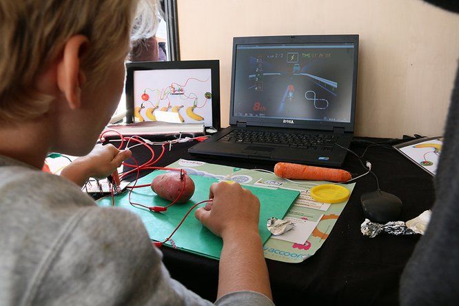 enfant en pleine expérimentation avec patates, carottes, câble, aluminium et ordinateurs