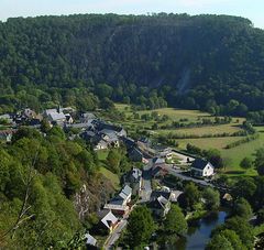 Vue aérienne d'un village entouré de verdure : prairie, bois, cours d'eau